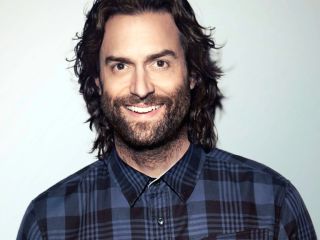 Chris D'Elia Wearing A Striped Shirt And Looking At The Camera