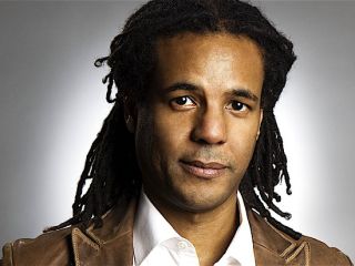 Colson Whitehead Wearing A Suit And Tie Smiling And Looking At The Camera