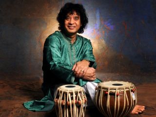 Zakir Hussain Sitting At A Table In Front Of A Cake